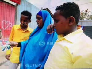 Fahmo Mantan Warsame and her children look at a photograph of Hanad Nuune Muhumed after a Reuters interview outside their home in Mogadishu, Somalia February 21, 2018. Picture taken February 21, 2018. REUTERS/Feisal Omar